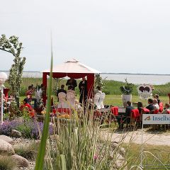 Inselhof VinetaWeitblick auf die freie Trauung unterm Hochzeitspavillon mit Gaesten auf der Festwiese