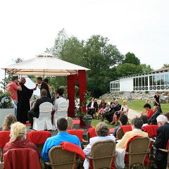 Inselhof Vineta Gaeste sitzen auf der Festwiese und beobachten die Trauung