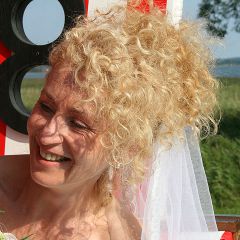 SChoene Braut sitzt laechelnd im Strandkorb