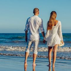 Imagebild Brautpaar spaziert barfuss am Strand
